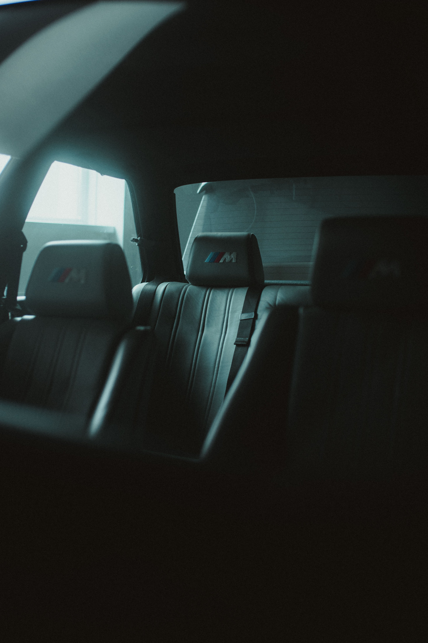 Leather rear seats with embroidered headrests, shot through a car window